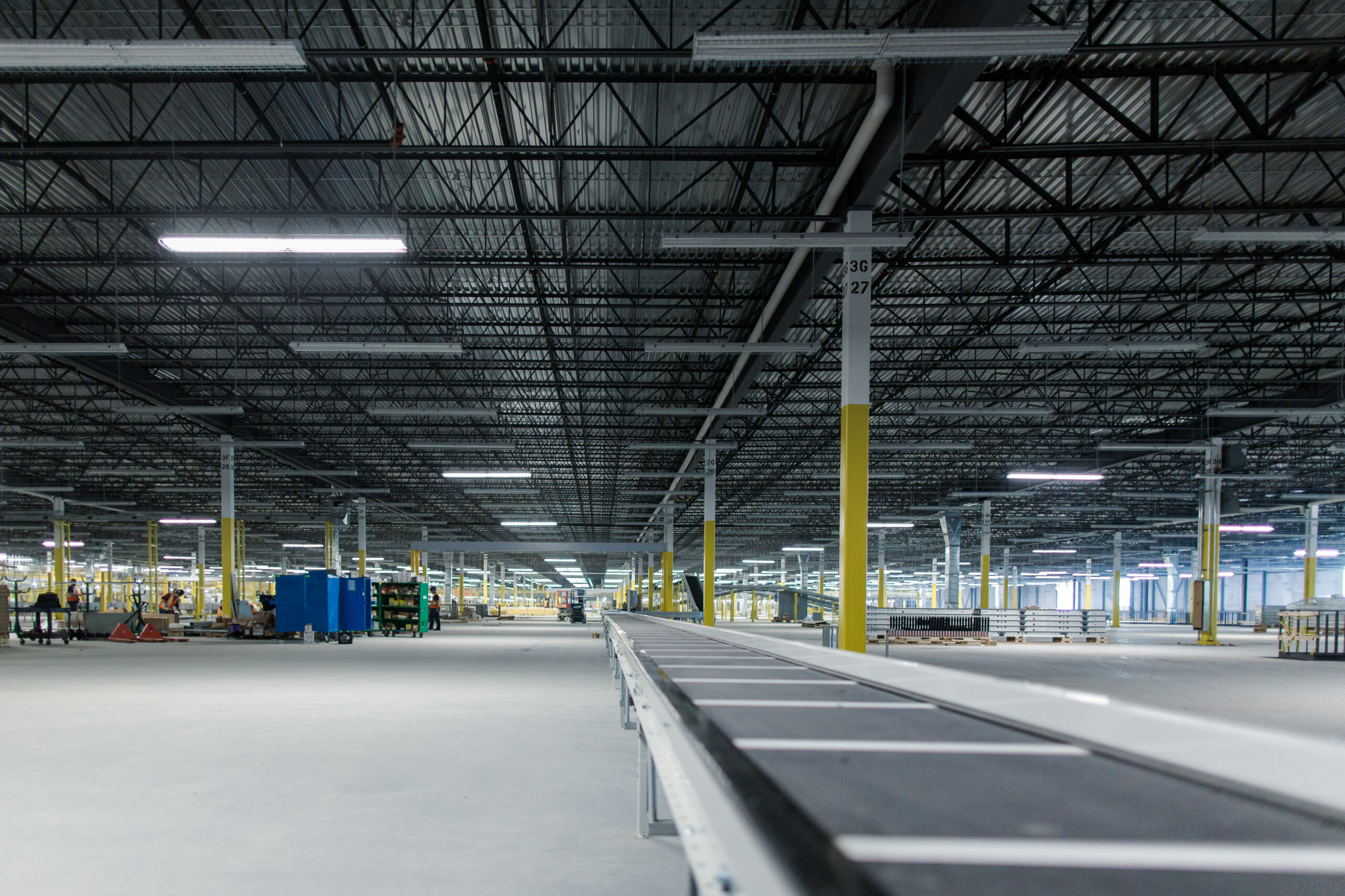 A long conveyor line extending across a large open warehouse with high ceilings and structural columns.
