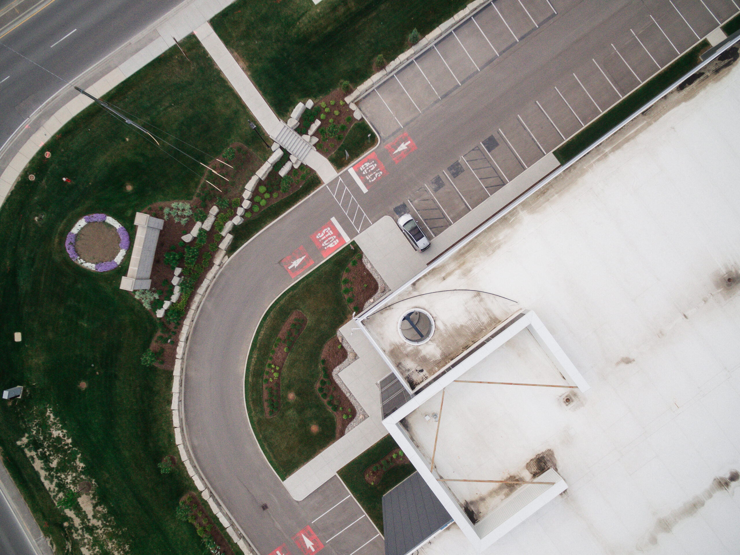 A top-down aerial view of a distribution facility entry drive, parking spaces, and landscaped areas.