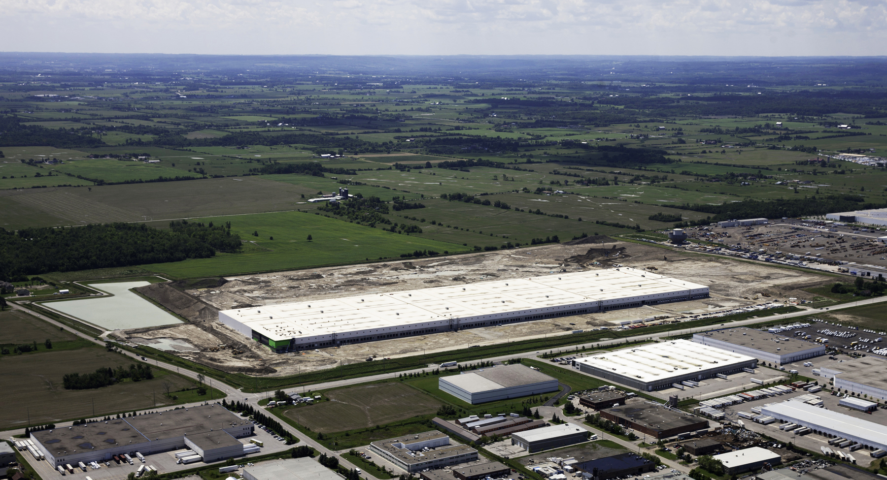 Aerial view of the Canadian Tire Bolton Distribution Centre, showing a large white industrial warehouse surrounded by fields and neighbouring commercial buildings.