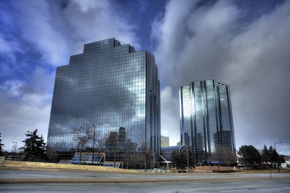 Exterior view of multiple glass office towers at Consilium Place under a cloudy sky.