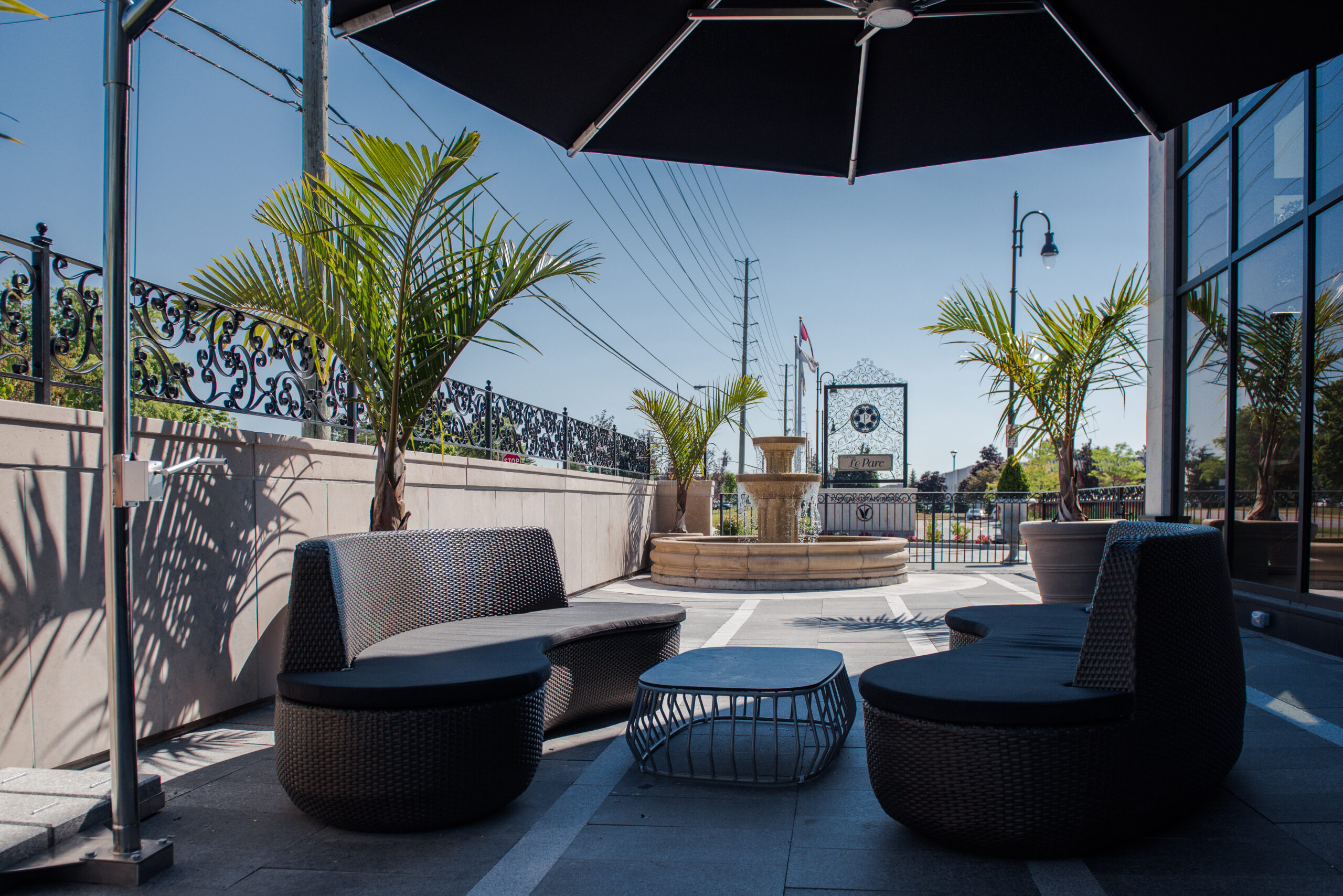 Outdoor terrace seating area with cushioned chairs, a central fire feature, and patio umbrellas.