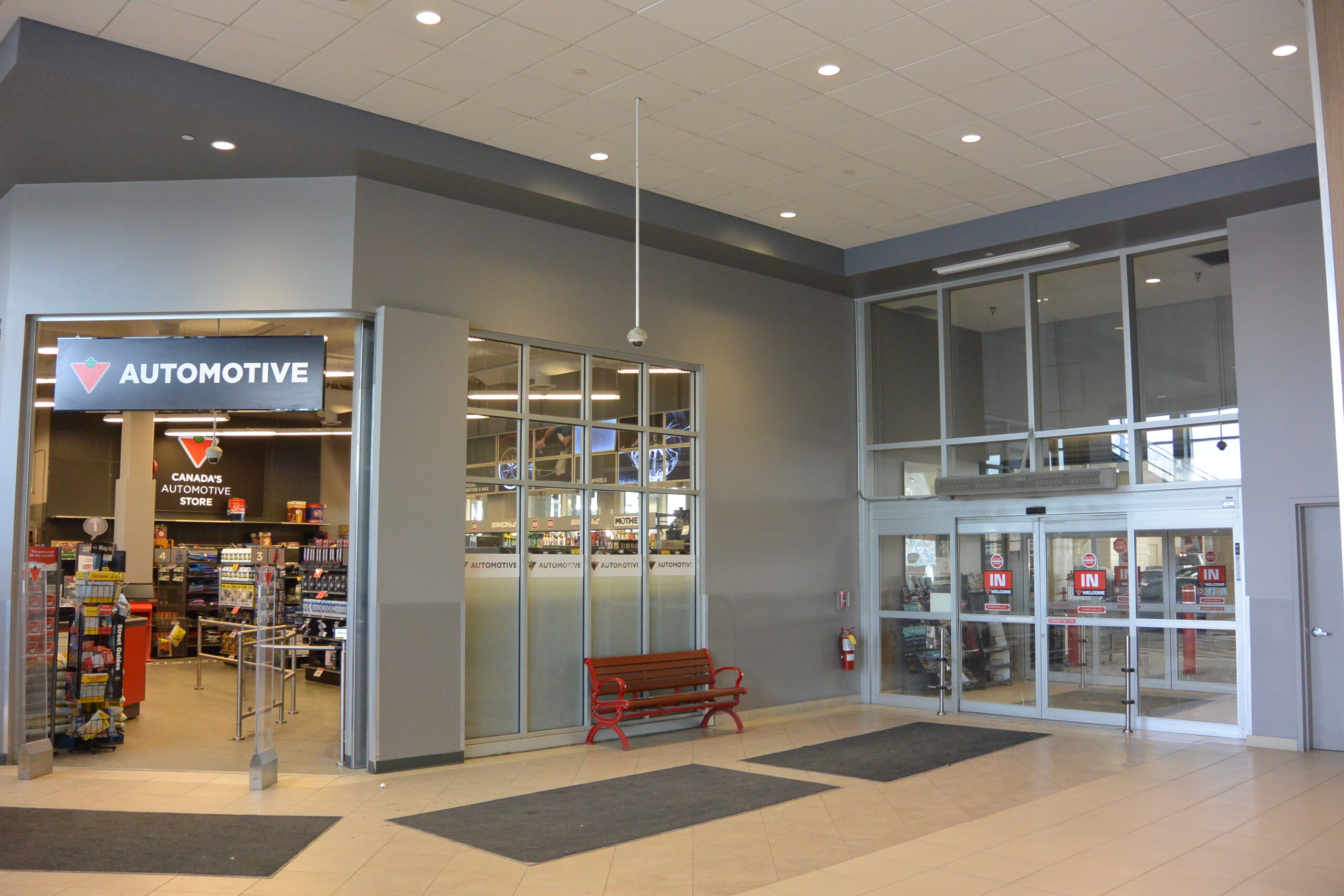 Interior entrance to the automotive service area of a Canadian Tire store with glass doors and waiting area seating.
