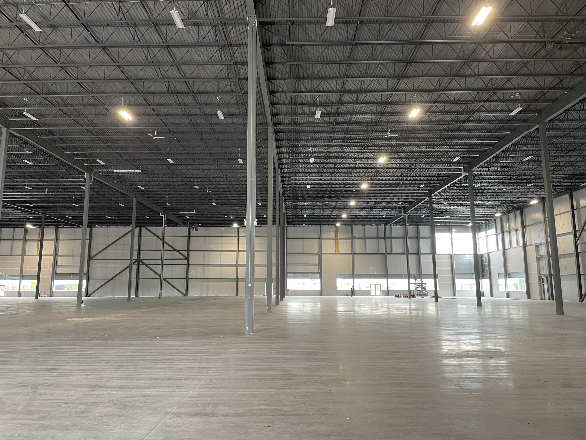 Empty warehouse interior at Northport Business Park with high ceilings, concrete floors, structural columns, and overhead lighting.