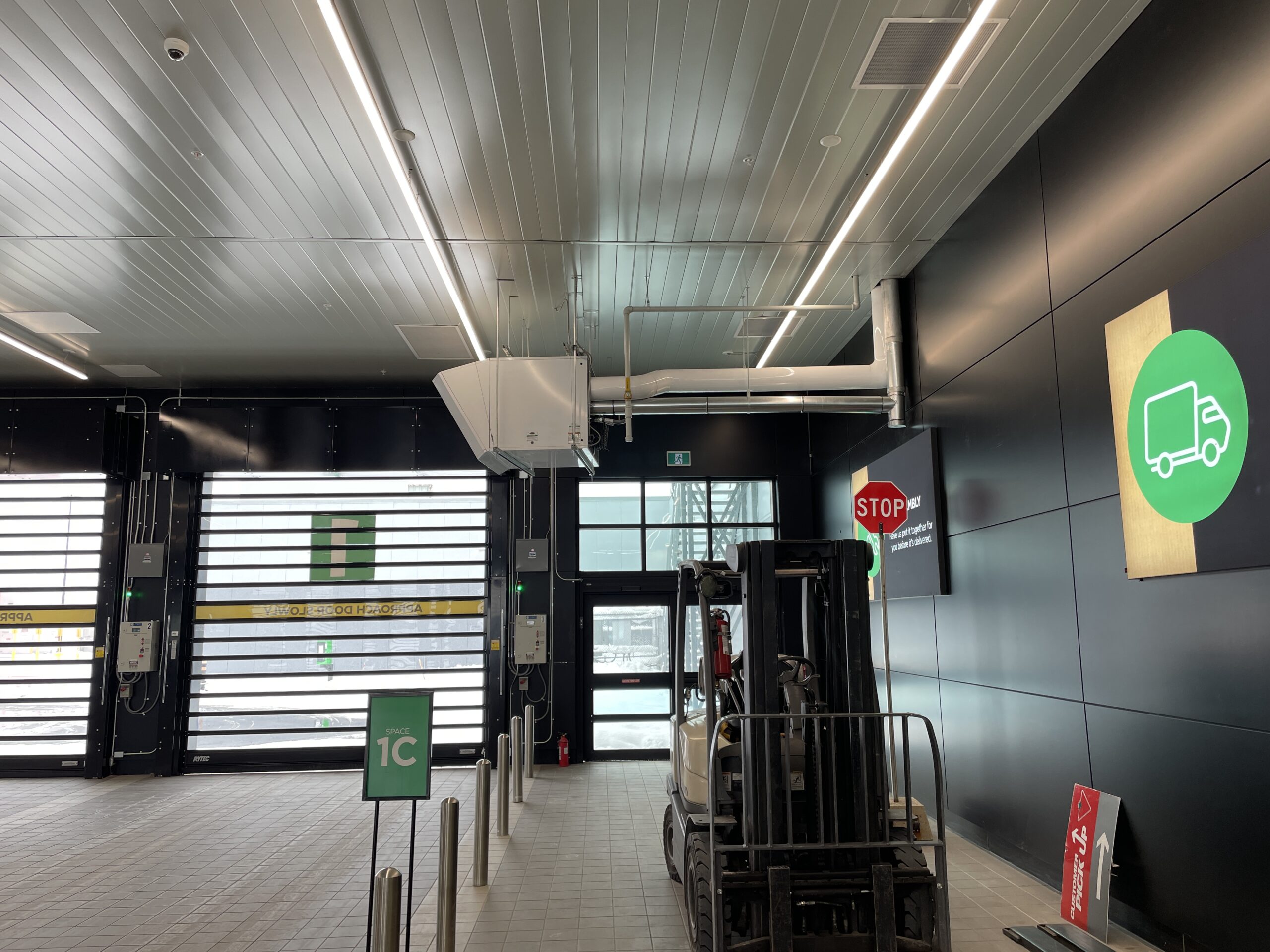 Interior service and loading area of a Canadian Tire store with overhead doors, safety signage, and material handling equipment.