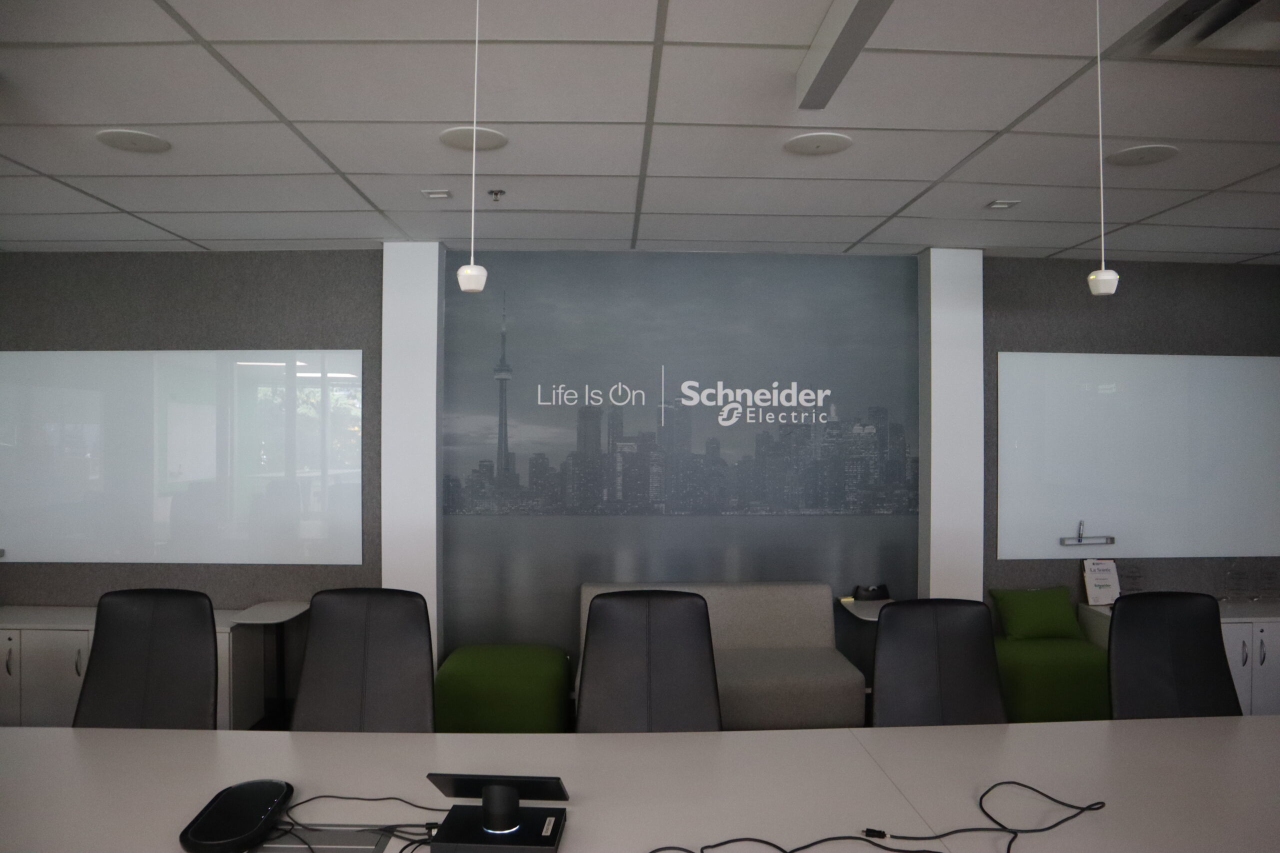 Meeting room with integrated audiovisual equipment, suspended lighting, and Schneider Electric branding at the Milton facility.