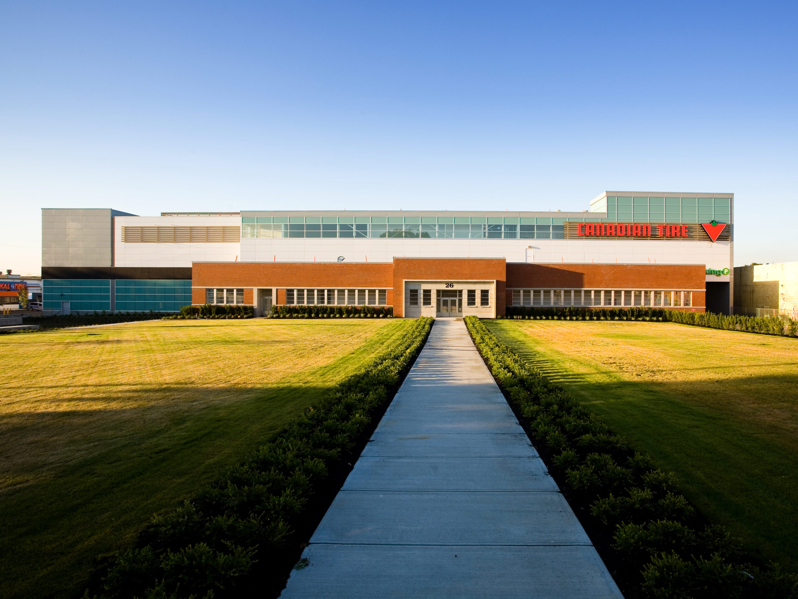 Exterior view of a large Canadian Tire building with landscaped grounds and a central pedestrian walkway leading to the entrance.