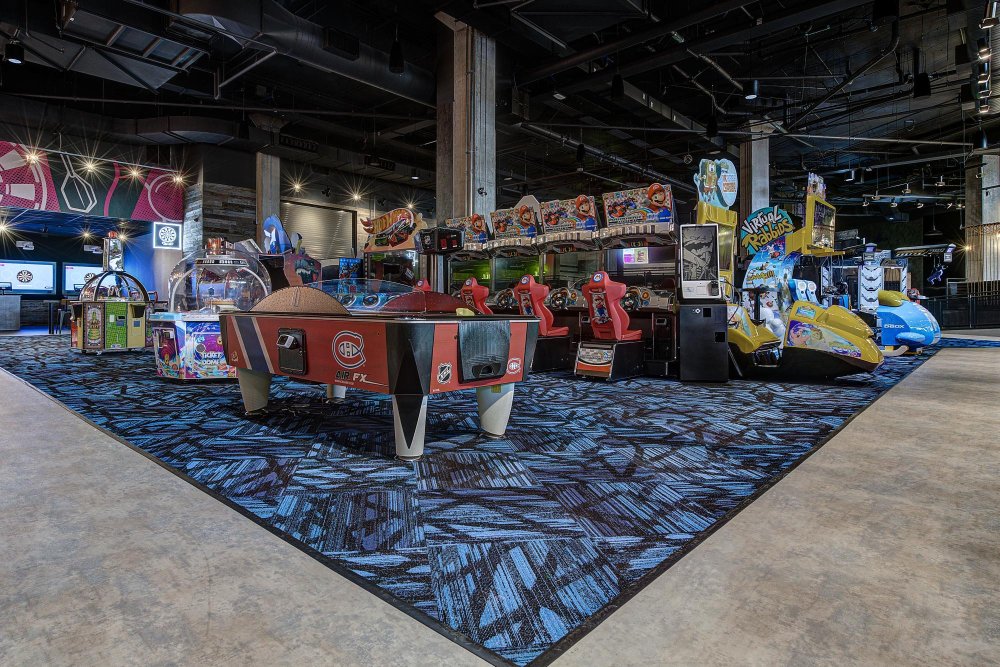Arcade floor with multiple game machines arranged on a patterned carpet.