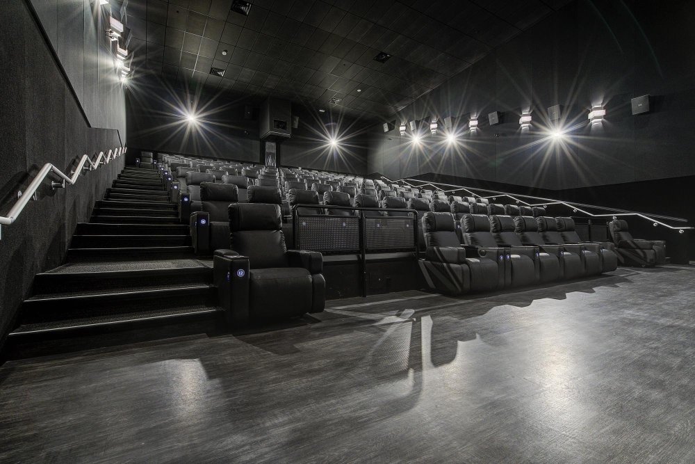 Empty movie theatre auditorium with tiered seating and a large screen.